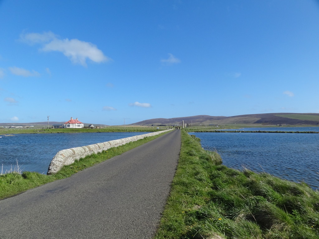 small road with water on both sides, leading to a white building with red roof