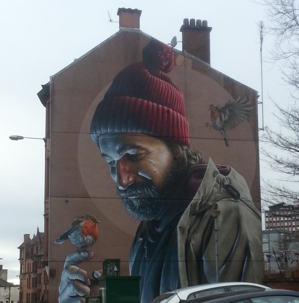 Artwork on a building. A man with a small bird perched on his finger