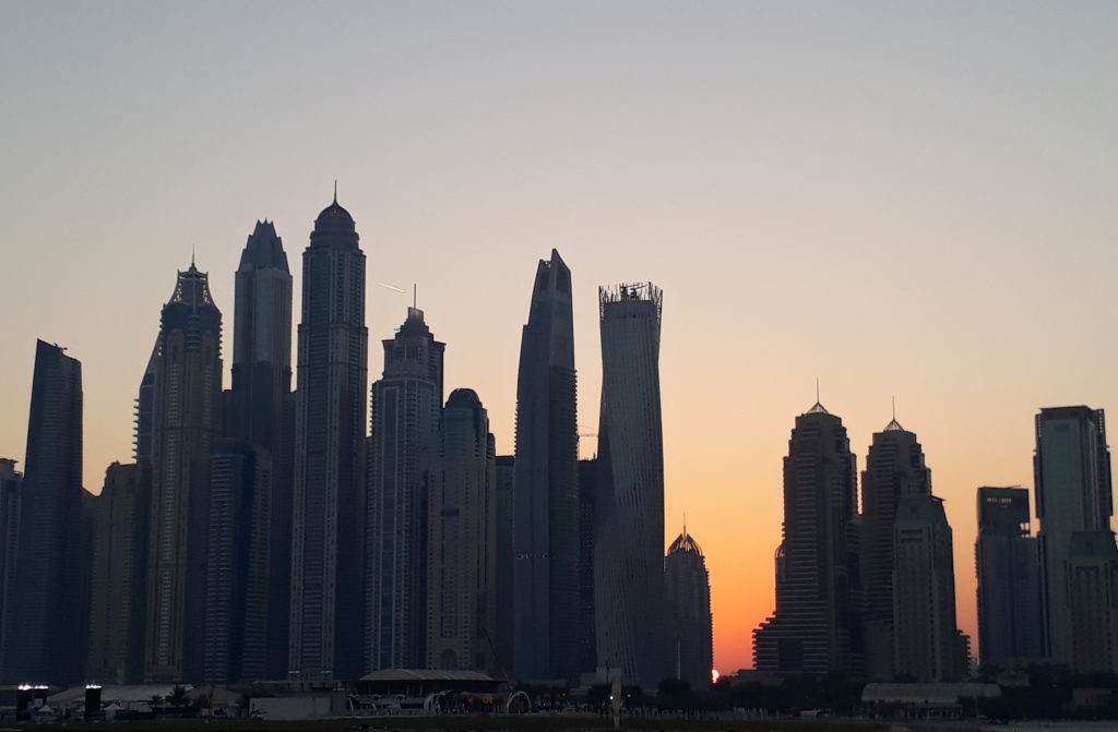 Sunrise behind dubai marina tower buildings
